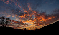 Tonight's dramatic Finger Lakes sunset featured vibrant orange and red clouds against a deep blue sky, creating a stunning contrast with the dark silhouettes of hills and trees, evoking a sense of cal